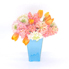 Lade das Bild in den Galerie-Viewer, Du siehst eine blaue Blumenvase. Das eckige Gefäß ist mit einem Blumenstrauß gefüllt.