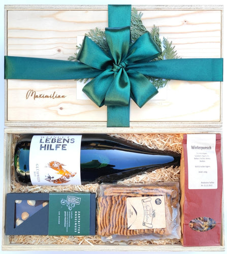 Unsere Wieihnachtsmarkt Geschenkbox beinhaltet köstlichen Bio Glühwein, Bio Früchtetee, Bio Spekulatius Plätzchen und eine leckere  Schokoladentafel. Auf dem Bild sieht du oben eine geschlossene Box mit Namens-Gravur und grüner Schleife verpackt. Darunter siehst du die gleiche Boxen offen ohne Decke mit den genannten Produkten in die Box gelegt.