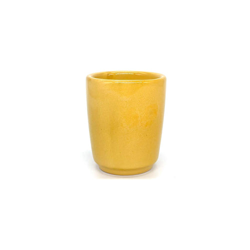 Auf dem Bild erkennst du ein kleines Glas, um darin Espresso zu trinken. Es ist in der Farbe gelb und besteht aus Keramik.

