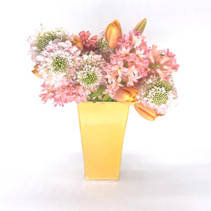 Das Bild zeigt eine gelbe Vase. Das Gefäß lässt sich perfekt mit Blumen beschmücken.