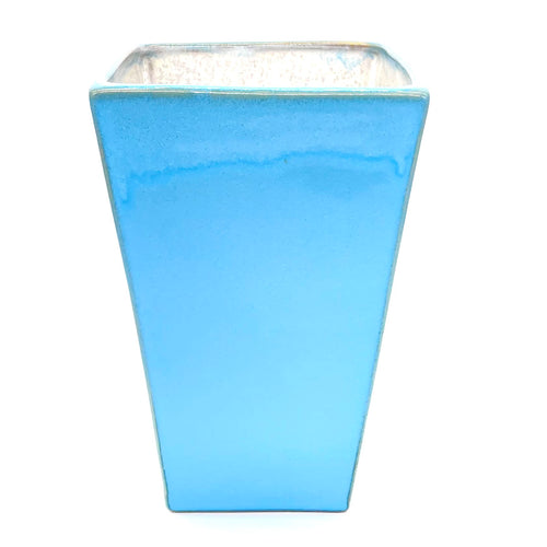 Du siehst eine eckige Vase. Sie ist blau und du kannst sie für Blumengestecke verwenden.
