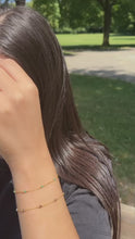 Laden und Abspielen von Videos im Galerie-Viewer, Im Video steckt eine Frau ihre Haare hinter´s Ohr. Dabei präsentiert sie ihre Ohrringe und ihre Armbänder. Im ersten Ohrloch trägt sie einen goldenen Hängeohrring. An dem Hängeohrring hängt eine kleine, goldene Kugel. Im zweiten Ohrloch trägt sie einen kleinen, goldenen Ohrstecker. An ihrem Arm trägt sie zwei goldene Armketten mit Steinchen. Auf dem ersten Armband sind türkise Steinchen, auf dem zweiten lila Steinchen.
