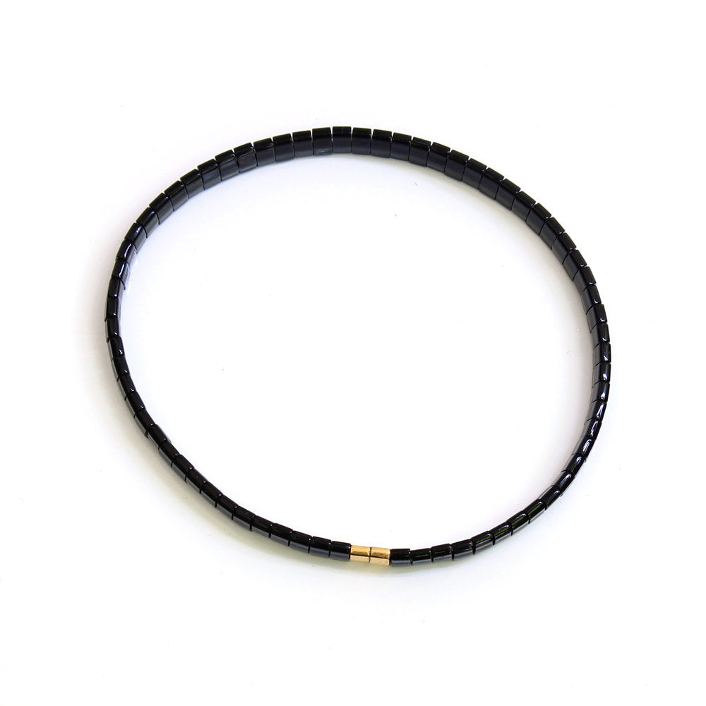 Hier siehst du ein schwarz farbenes Armband aus Perlen mit 2 Goldperlen unten